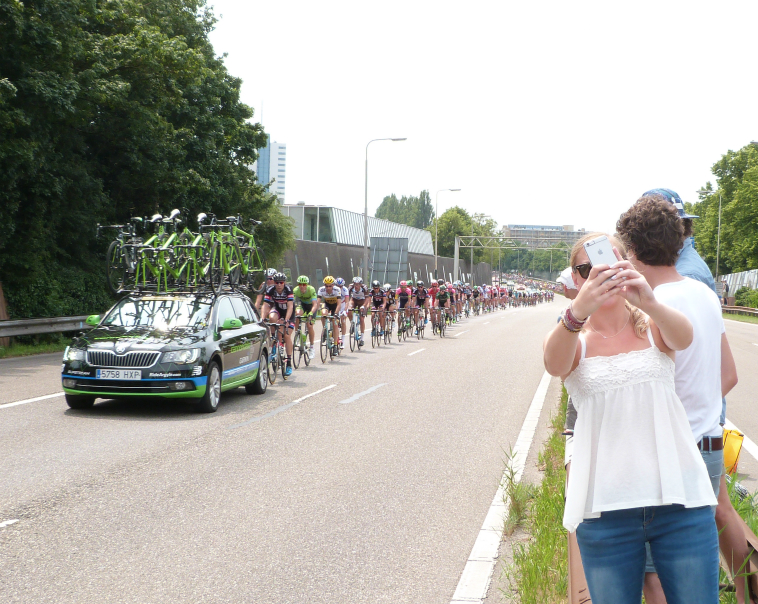 A spectator takes a selfie in front of the peloton